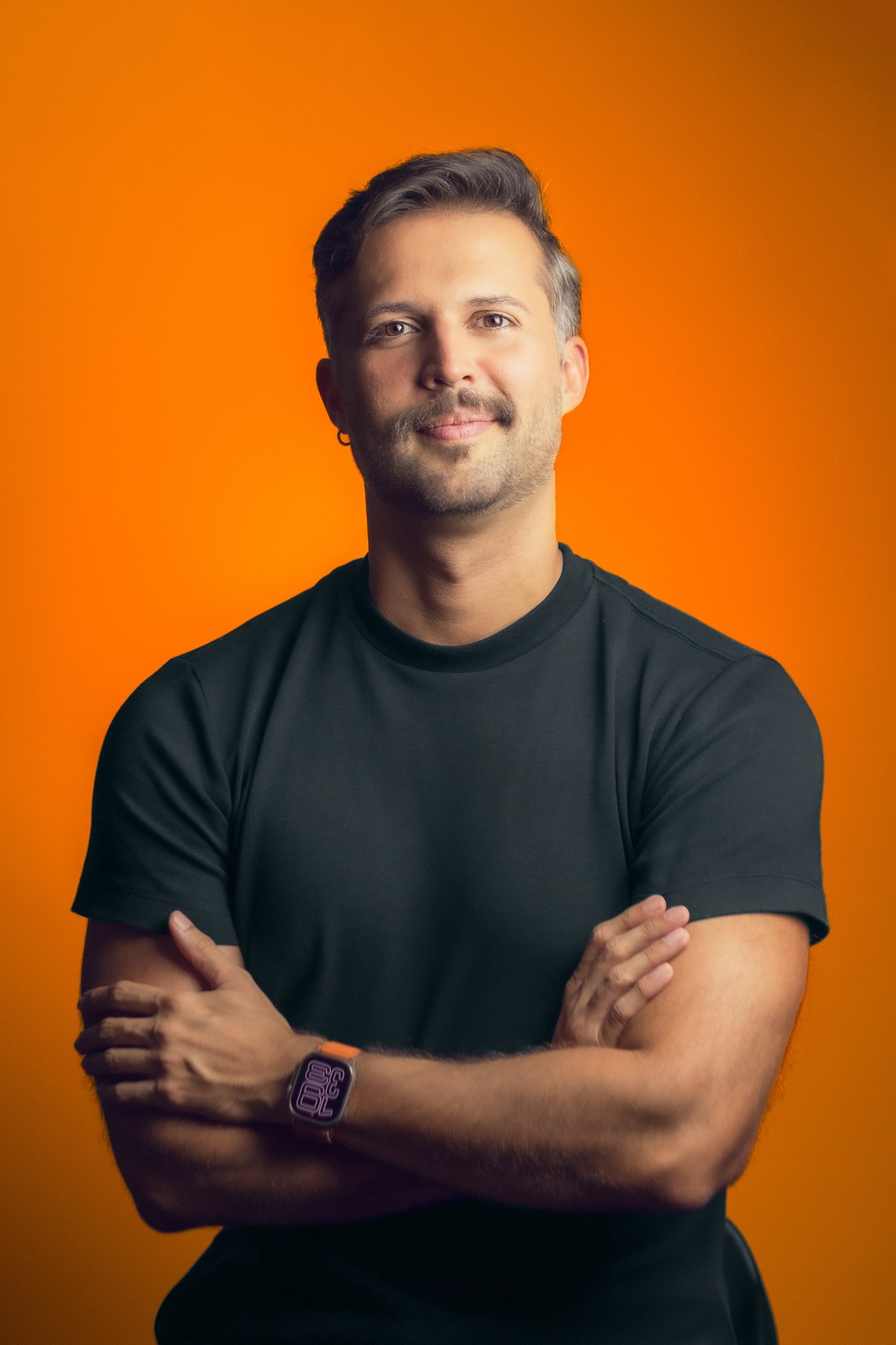 Galileu Nogueira, especialista em branding e fundador da Galileo Branding, em retrato profissional sobre fundo laranja